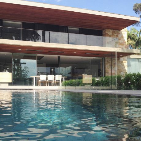 Elegant modern home with wood exterior, glass walls, and pool in lush landscape.