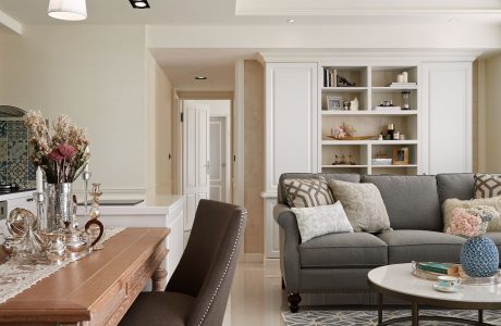 Elegant living space with wooden dining table, grey sofa, and open shelving.