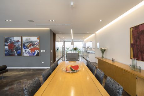 Sleek, modern interior with colorful artworks, minimalist dining table and integrated kitchen.