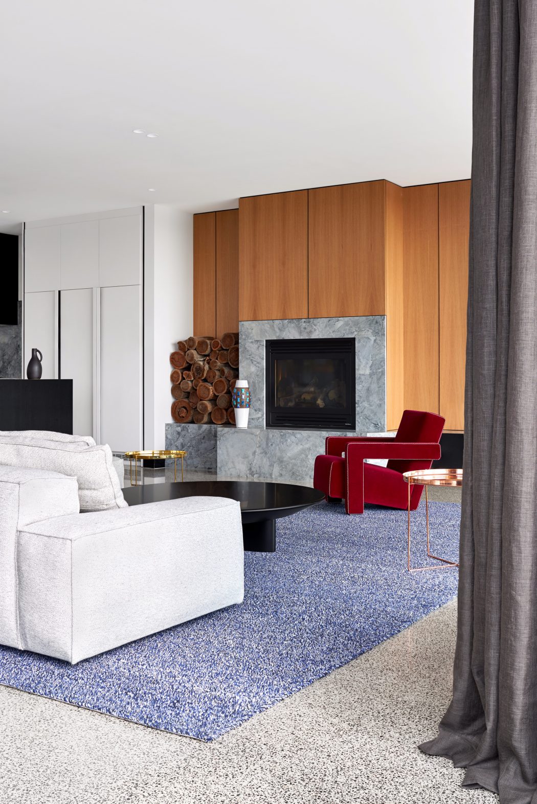 Stylish modern living room with wood-paneled wall, marble fireplace, and plush seating.