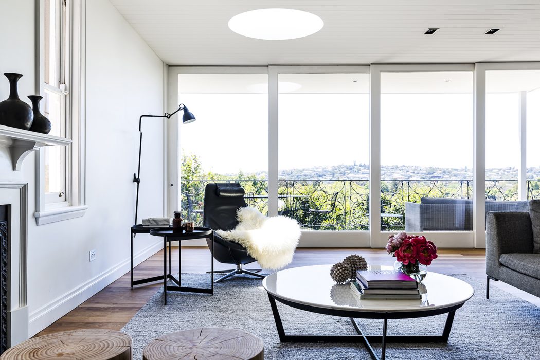 A modern, bright living room with floor-to-ceiling windows, sleek furniture, and cozy accents.