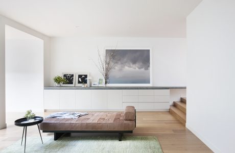 Minimalist living space with wooden floor, gray cabinetry, and leather sofa.