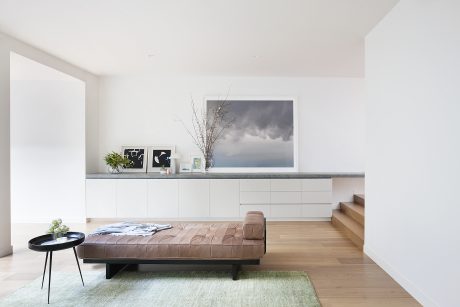 Minimalist living space with wooden floor, gray cabinetry, and leather sofa.