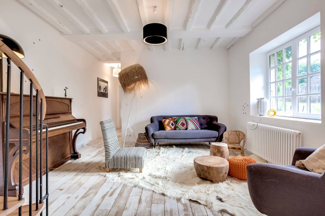 A cozy living space with a piano, wooden beams, and an eclectic mix of furnishings.