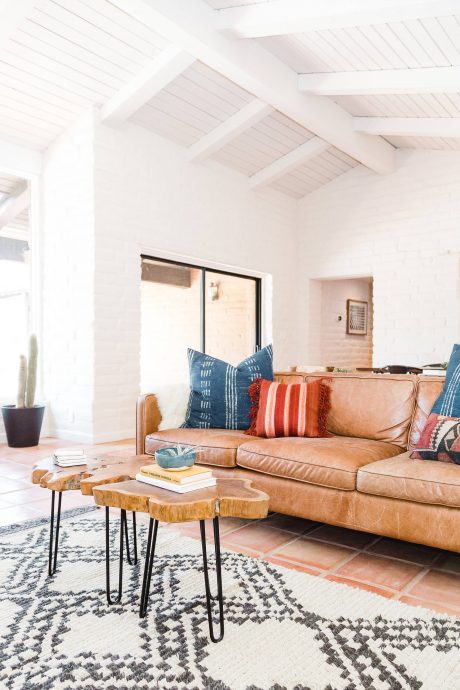 Spacious living room with high ceiling, wooden furniture, and boho-chic decor.