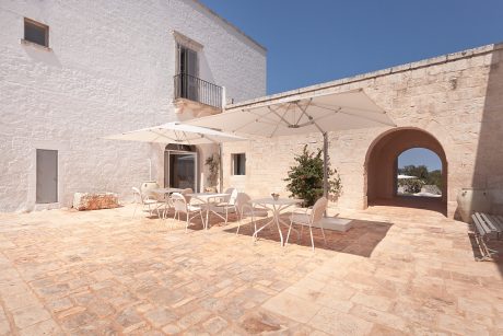Picturesque Mediterranean-style courtyard with white umbrellas and stone architecture.