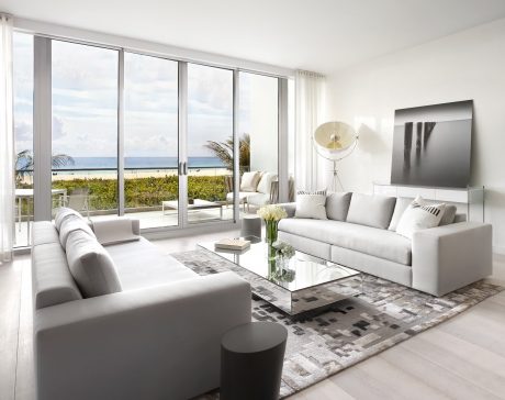 Spacious living room with contemporary decor, large windows providing panoramic ocean view.