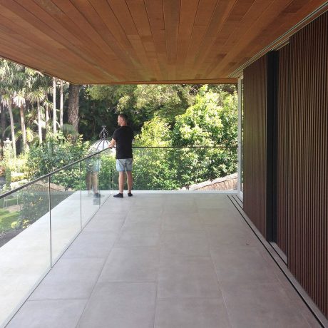 A modern wooden ceiling and exterior view with a person standing on a concrete patio.