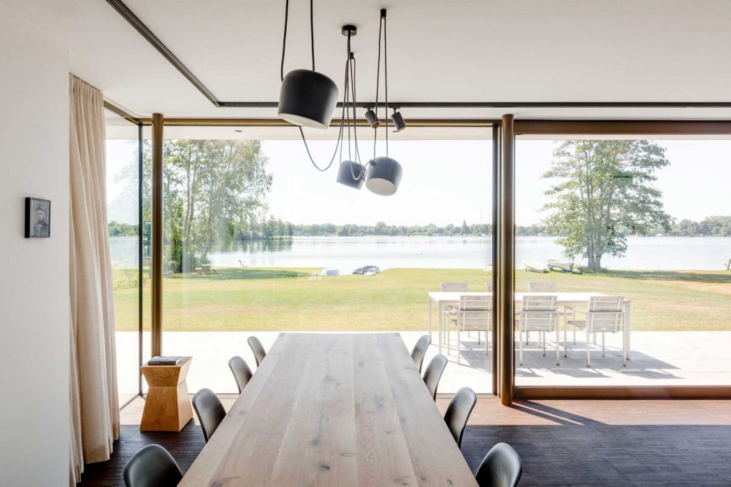 Sleek, modern dining area with large glass doors showcasing scenic lakefront view.