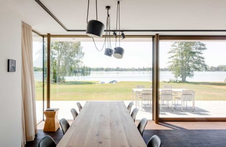 Sleek, modern dining area with large glass doors showcasing scenic lakefront view.