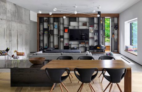 A modern, minimalist living room with a concrete wall, wood accents, and stylish furniture.