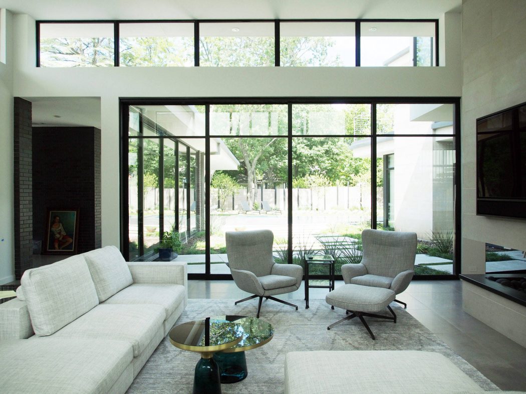 Spacious modern living room with large windows overlooking a lush outdoor garden.