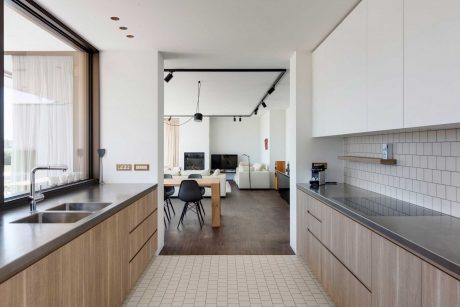 Minimalist kitchen with wooden cabinetry, subway tile backsplash, and open living space.