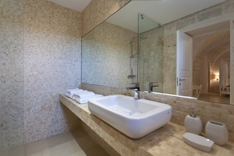 Luxurious bathroom with beige mosaic tiles, modern sink, and glass-enclosed shower.