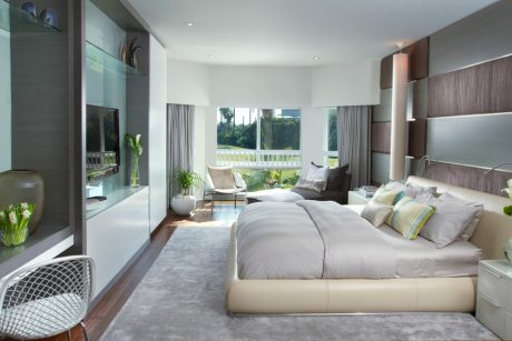 Spacious modern bedroom with floor-to-ceiling windows, plush furnishings, and nature-inspired decor.