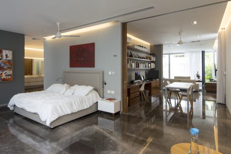 Spacious, modern bedroom with minimalist furniture and sleek, glossy flooring.