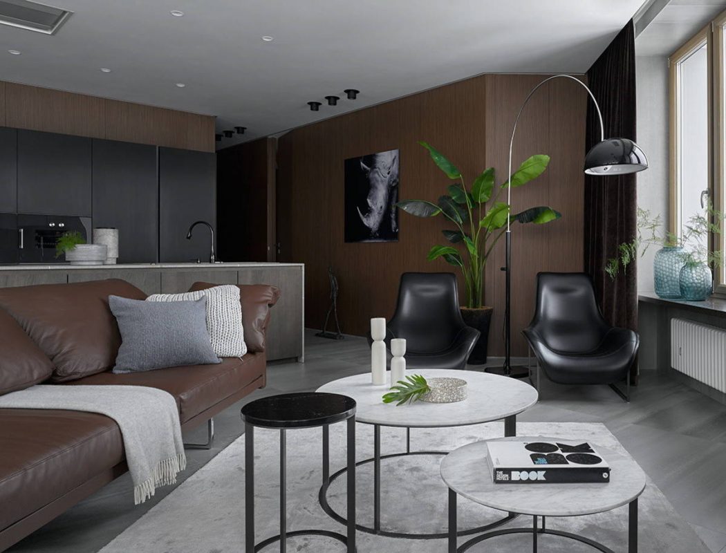 Sleek, modern living space featuring dark wood accents, stylish furniture, and lush greenery.