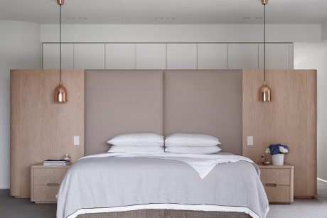 Minimalist bedroom with wood accents, copper pendant lights, and built-in storage.