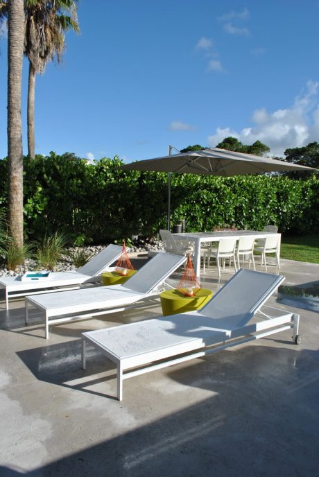 Sleek outdoor patio furniture in modern design, surrounded by lush greenery and a clear sky.