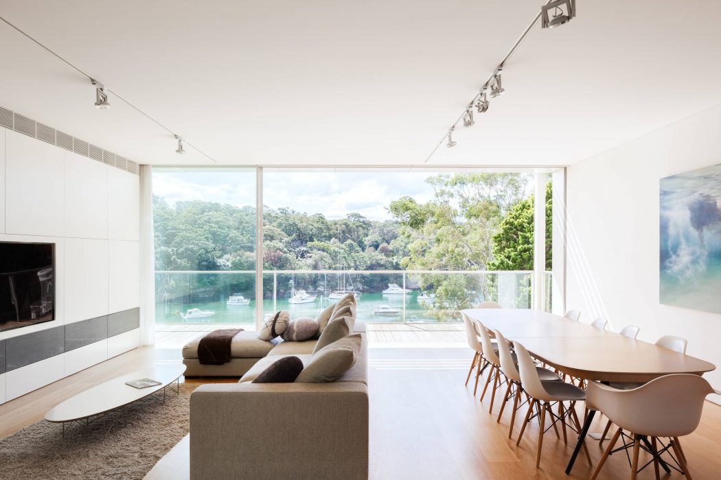 Sleek, modern living space with expansive glass windows overlooking lush greenery and boats.