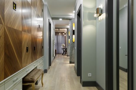 A modern, well-lit hallway with wooden paneling, built-in storage, and decorative lighting.