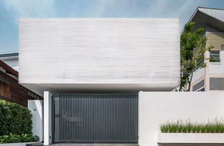 A modern, minimalist building with a clean white facade, contrasting with the dark metal gate.