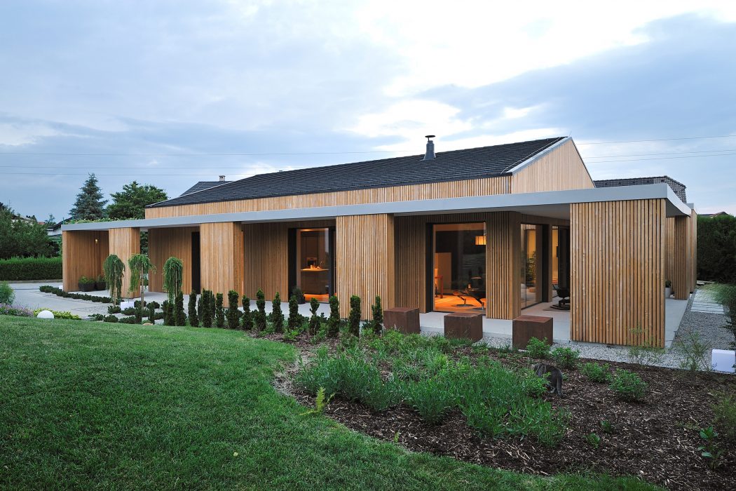 Modern single-story house with wood siding, large windows, and landscaped grounds.