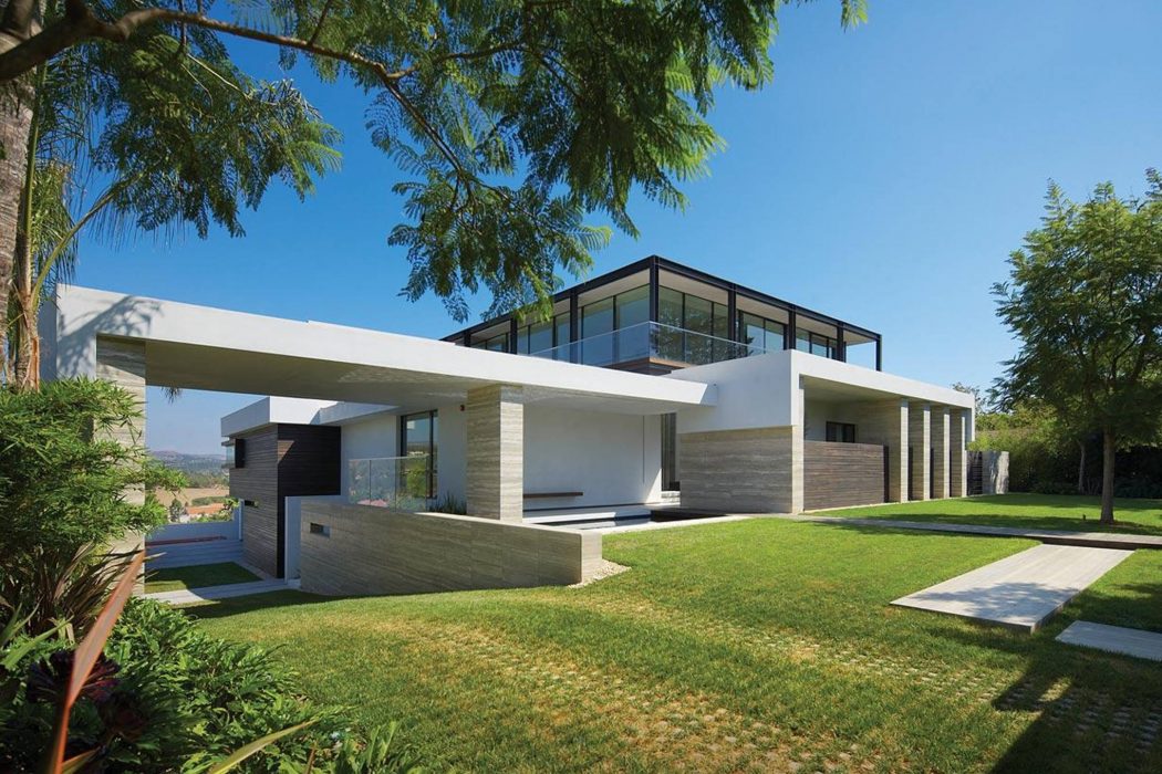 Sleek modern home with clean lines, large windows, and lush landscaping.