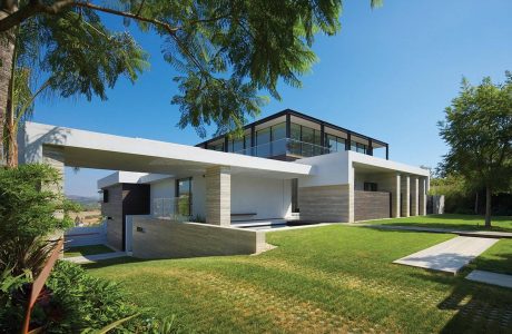 Sleek modern home with clean lines, large windows, and lush landscaping.