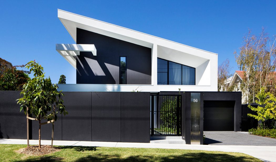 Modern two-story home with sleek black facade, angular roofline, and large windows.