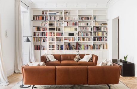 Spacious living room with floor-to-ceiling bookshelves, cozy leather sofa, and hardwood floors.