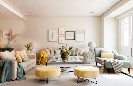 Cozy living room with soft pastel tones, framed art, and textured furnishings.