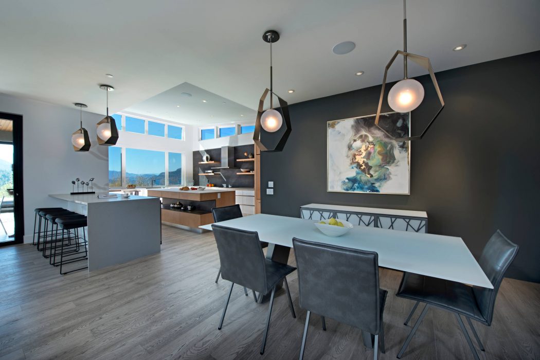 Sleek modern kitchen and dining room with geometric light fixtures, grey and wood tones.