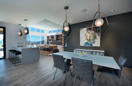 Sleek modern kitchen and dining room with geometric light fixtures, grey and wood tones.