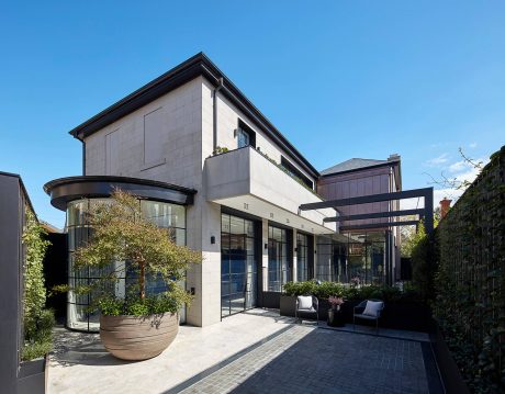 Architectural details of a contemporary multi-story building with glass facade, balconies, and landscaping.