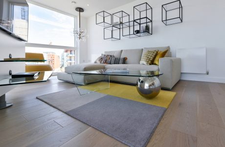 Minimalist living room with geometric shelves, plush sectional, and oversized glass coffee table.