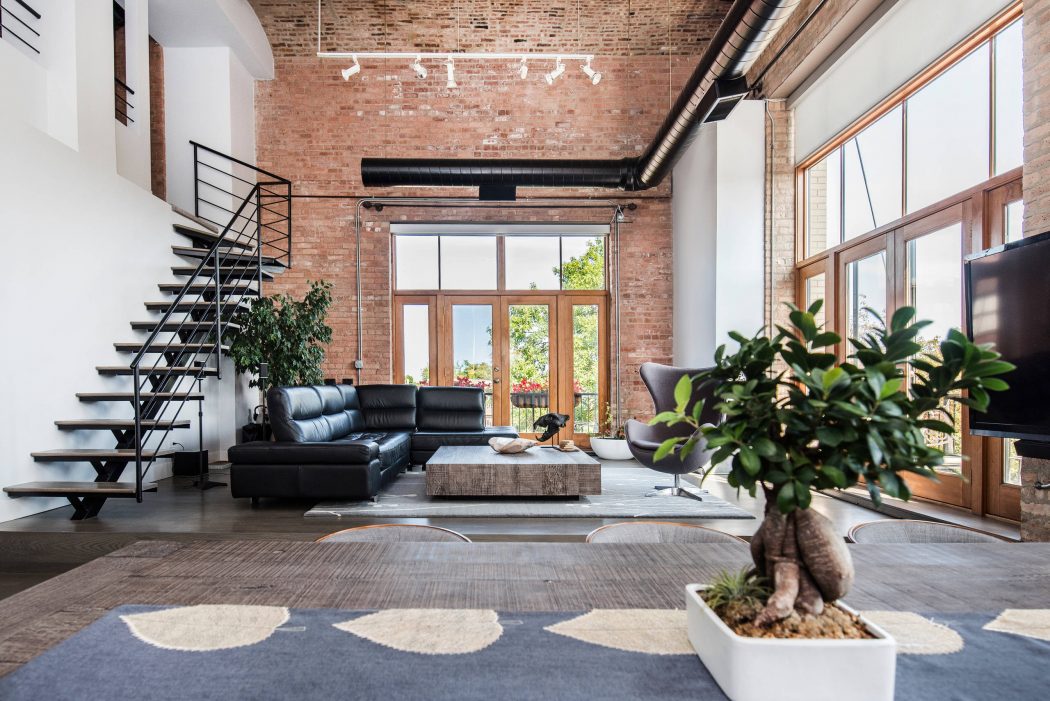 Chic industrial-style loft with brick walls, minimalist furnishings, and large windows.