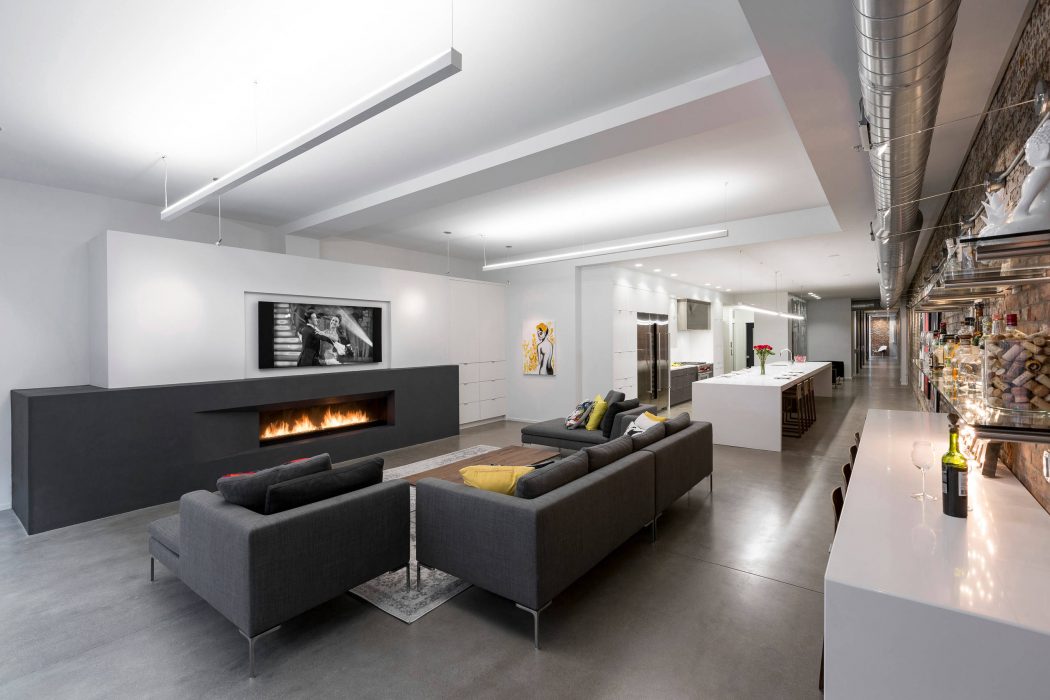 A modern, open-concept living space with a sleek fireplace, couches, and an artistic gallery wall.