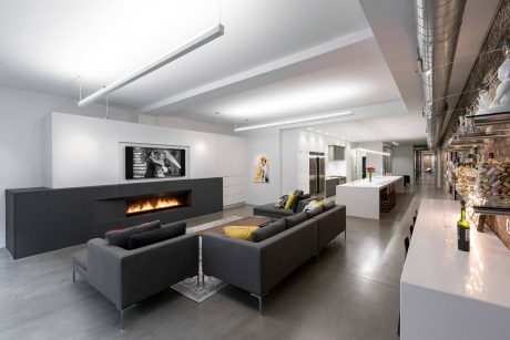 A modern, open-concept living space with a sleek fireplace, couches, and an artistic gallery wall.