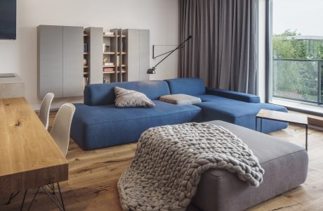Spacious living room with blue sofa, wooden floor, and built-in shelving units.