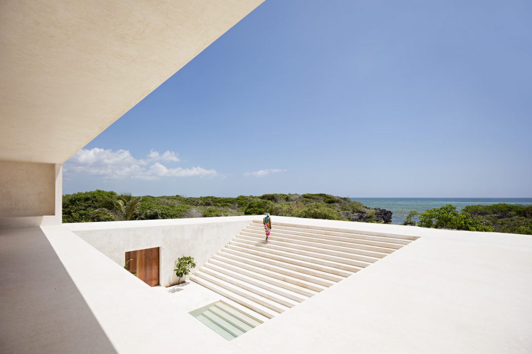 Striking minimalist architecture with staircase leading towards lush coastal landscape.