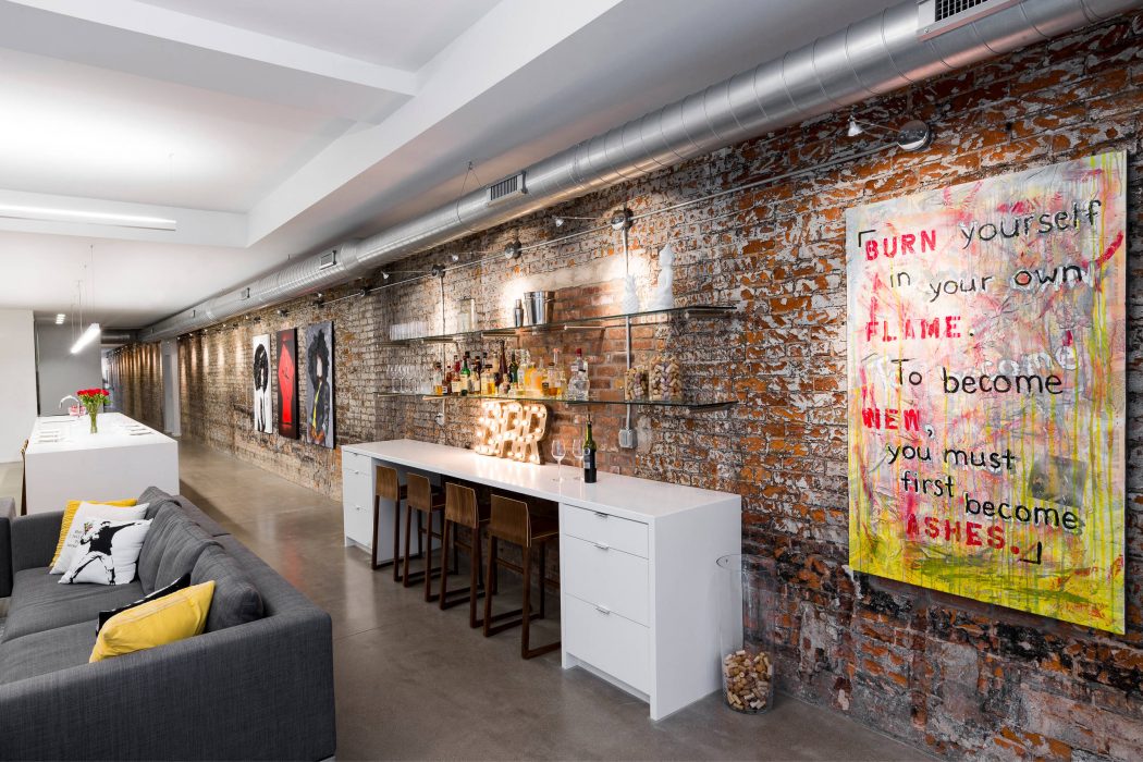 Striking industrial-style space with exposed brick walls, built-in bar, and vibrant graffiti art.