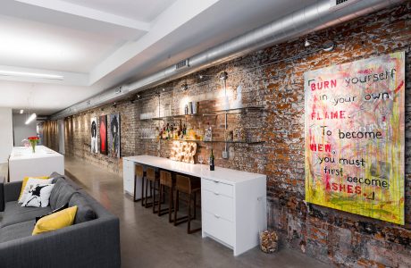 Striking industrial-style space with exposed brick walls, built-in bar, and vibrant graffiti art.