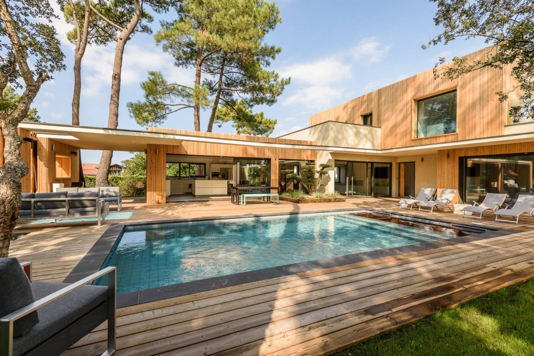 Sprawling modern wooden residence with large pool and outdoor living area.