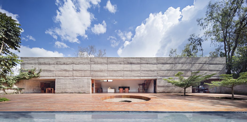 Modern concrete structure with recessed entrance, courtyard, and reflecting pool.