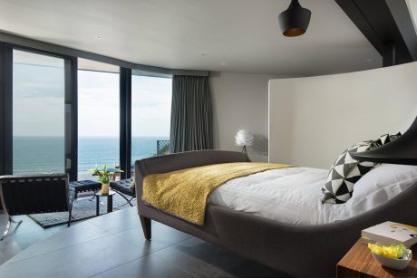 Spacious bedroom with panoramic ocean view, modern furniture, and stylish lighting.