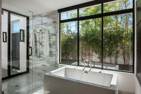 Spacious bathroom with sleek modern design, large windows overlooking lush greenery.