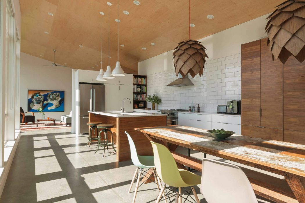 A modern kitchen with wooden beams, subway tiles, and a rustic dining table.