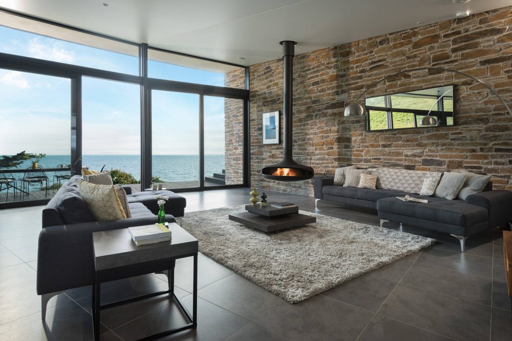 Spacious living room with panoramic windows, stone fireplace, and contemporary furniture.