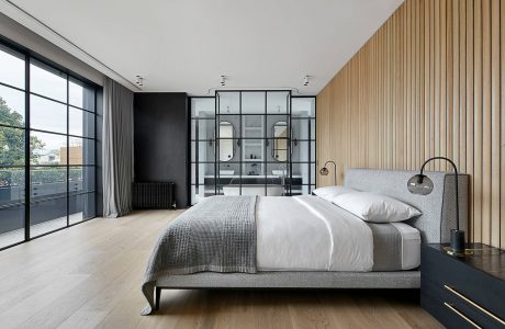 Modern bedroom with floor-to-ceiling windows, wooden accent wall, and glass-enclosed bathroom.